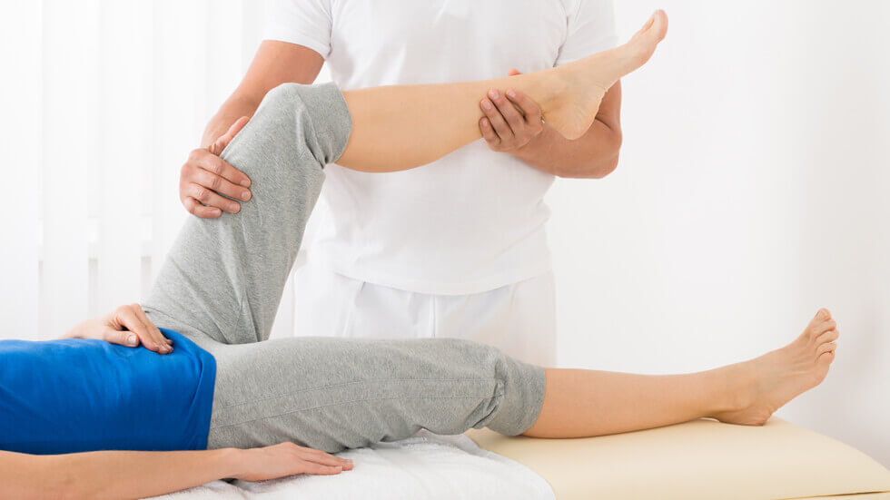 Physiotherapeut behandelt Knie einer Patientin