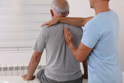 Chiropraktiker / Osteopath behandelt den Rücken eines älteren Patienten