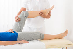 Physiotherapeut behandelt Knie einer Patientin